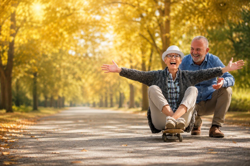 Joyful senior couple laughing together on a tree-lined autumn path
